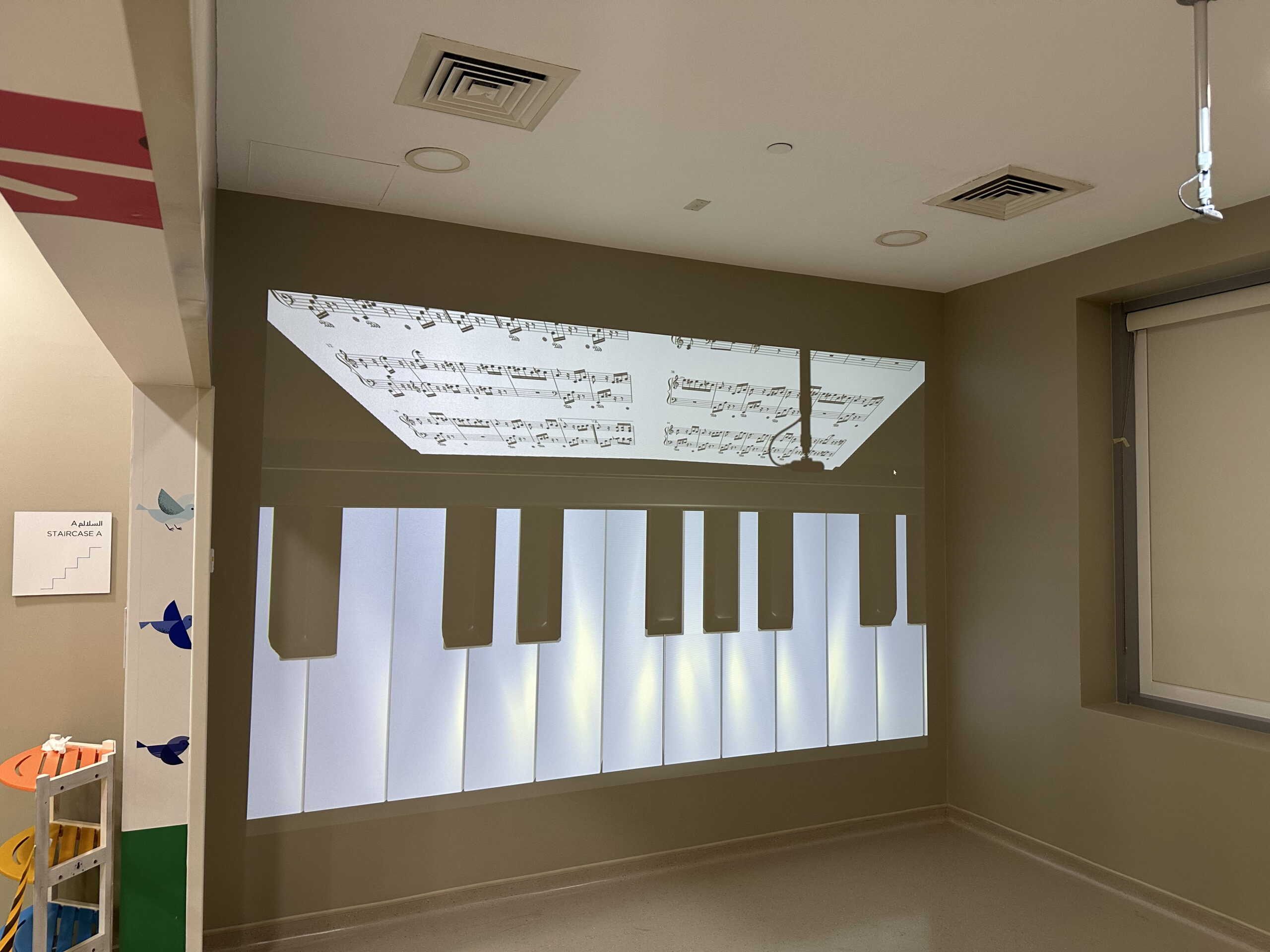 Children playing with an interactive projection wall using physical balls at MediClinic Dubai.