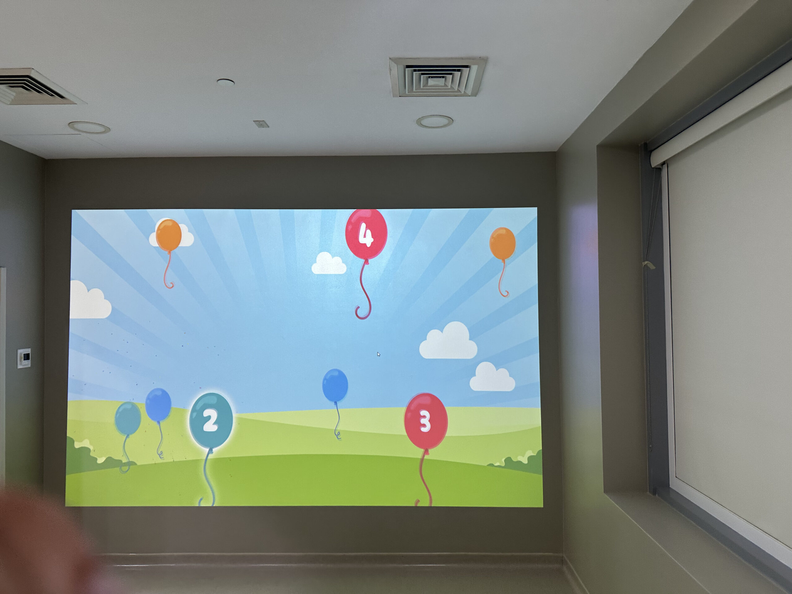 Children playing with an interactive projection wall using physical balls at MediClinic Dubai.