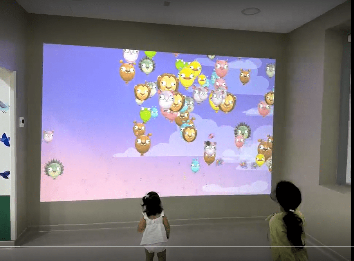 Children playing with an interactive projection wall using physical balls at MediClinic Dubai.