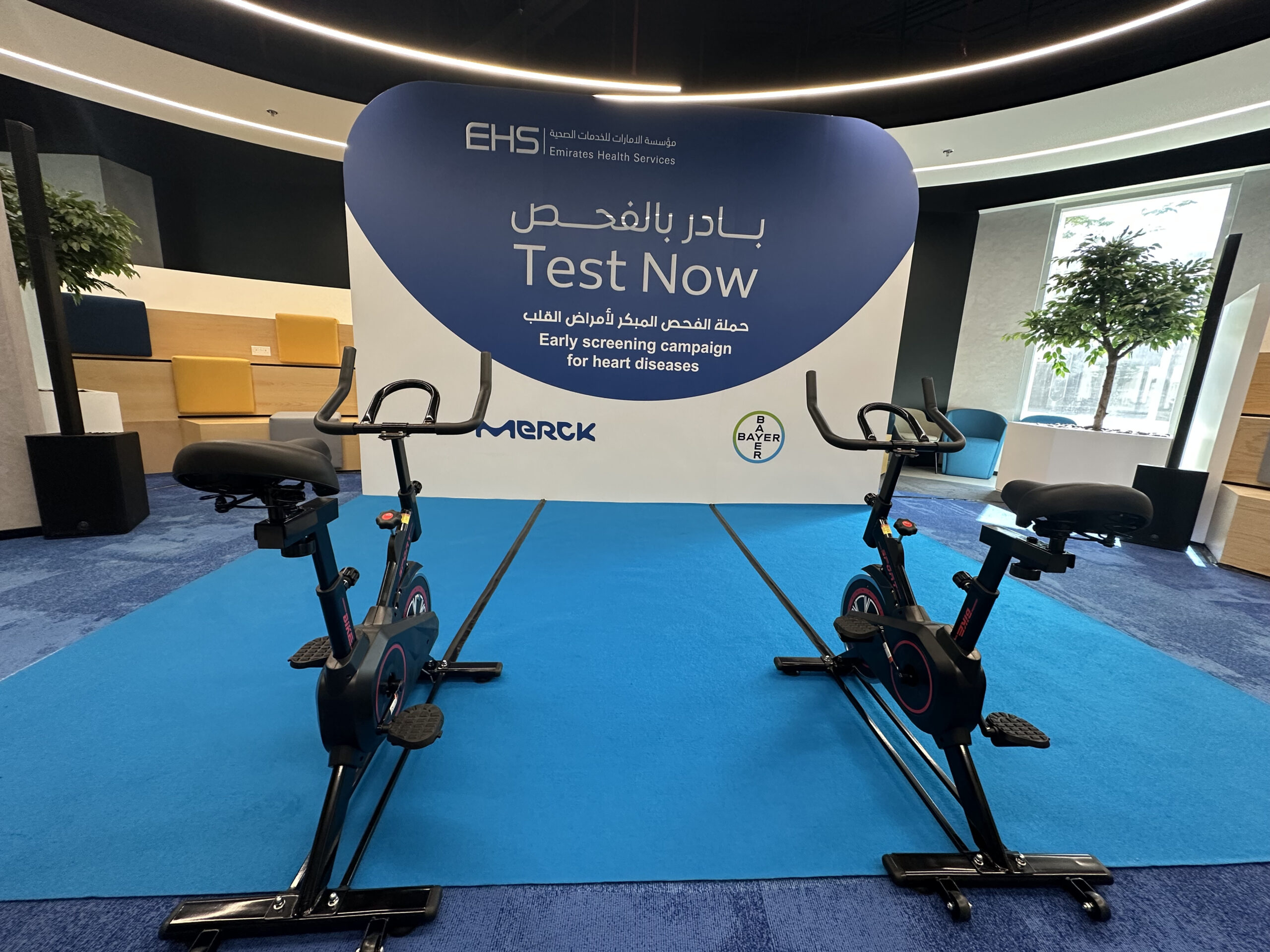 Two users competing on stationary bikes for the EHS early heart screening campaign.