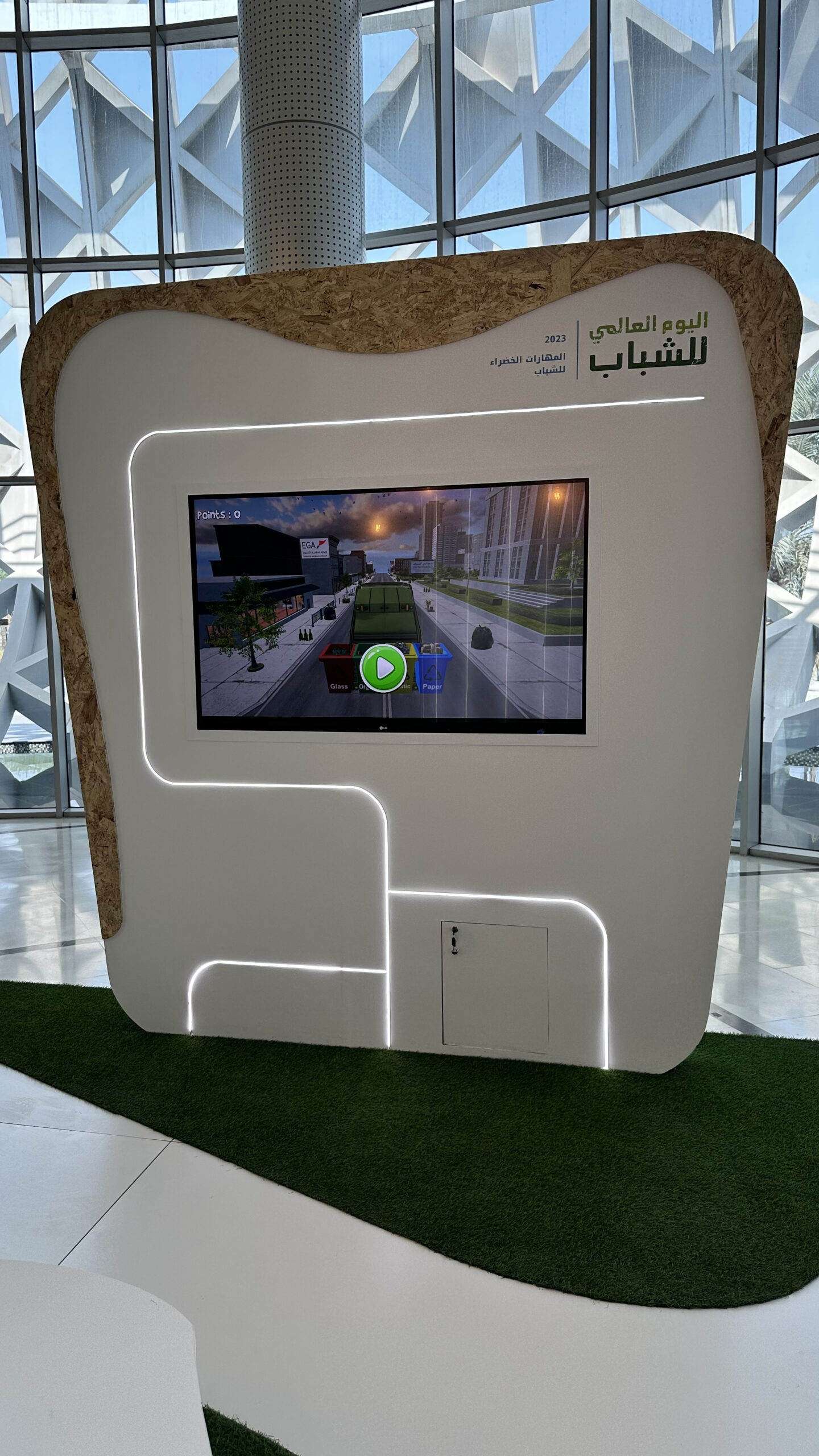 Visitors playing the EGA Youth Council interactive waste segregation game on a touch kiosk.